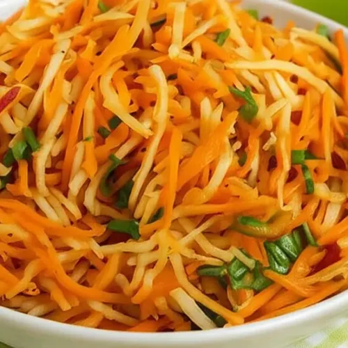 Frisch zubereiteter Kohlrabi-Karotten-Apfel-Salat in einer weißen Schüssel